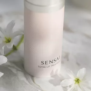 Close up of SENSAI's Total Lip Treatment pack shot on surface with flowers